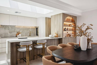 Inspiration for a mid-sized galley porcelain tile, gray floor and coffered ceiling eat-in kitchen remodel in Los Angeles with a drop-in sink, flat-panel cabinets, white cabinets, marble countertops, white backsplash, marble backsplash, stainless steel appliances, a peninsula and white countertops