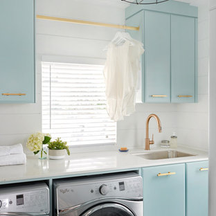 Retro single-wall separated utility room in Toronto with a submerged sink, flat-panel cabinets, blue cabinets, white walls and a side by side washer and dryer.