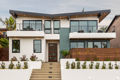 Example of a large trendy white two-story mixed siding house exterior design in San Diego with a mixed material roof and a shed roof