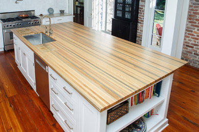 Example of a large trendy dark wood floor and brown floor eat-in kitchen design in New Orleans with an undermount sink, beaded inset cabinets, white cabinets, wood countertops, stainless steel appliances, an island and brown countertops