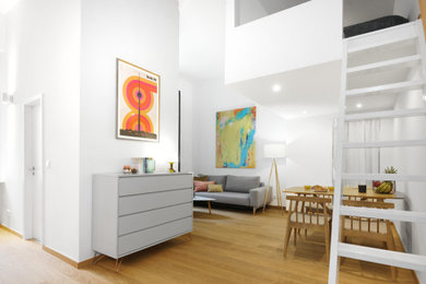 Small contemporary loft-style living room in Berlin with white walls, light hardwood floors, a freestanding tv and brown floor.