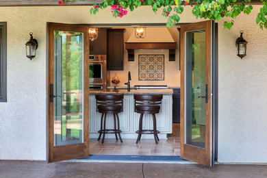Example of a mid-sized transitional l-shaped eat-in kitchen design in San Diego with a farmhouse sink, shaker cabinets, dark wood cabinets, granite countertops, white backsplash, ceramic backsplash, stainless steel appliances, an island and beige countertops