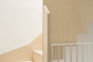 Réalisation d'un grand escalier minimaliste en U avec des marches en bois, des contremarches en bois et un garde-corps en bois.