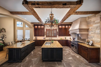 Example of a tuscan u-shaped gray floor kitchen design in Denver with an undermount sink, raised-panel cabinets, dark wood cabinets, beige backsplash, stainless steel appliances, an island and brown countertops