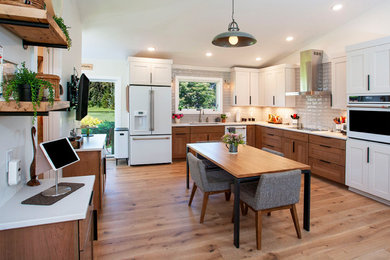 Large trendy l-shaped light wood floor, brown floor and vaulted ceiling eat-in kitchen photo in Other with an undermount sink, shaker cabinets, medium tone wood cabinets, quartz countertops, white backsplash, subway tile backsplash, white appliances, no island and white countertops