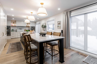 Example of a large trendy u-shaped light wood floor eat-in kitchen design in Montreal with a farmhouse sink, shaker cabinets, white cabinets, quartz countertops, an island and white countertops
