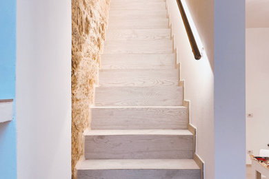 Imagen de escalera recta mediterránea pequeña con escalones de madera, contrahuellas de madera, barandilla de metal y ladrillo