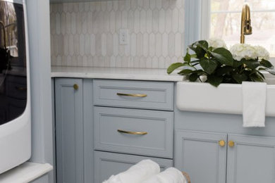 Modelo de cuarto de lavado de galera pequeño con fregadero sobremueble, armarios estilo shaker, puertas de armario azules, encimera de cuarcita, lavadora y secadora juntas y encimeras blancas