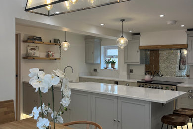 Medium sized traditional grey and purple galley kitchen in Berkshire with a belfast sink, shaker cabinets, grey cabinets, quartz worktops, metallic splashback, mirror splashback, stainless steel appliances, porcelain flooring, a breakfast bar, grey floors, white worktops, a vaulted ceiling and feature lighting.