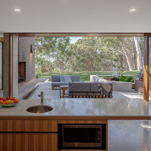 Idéer för ett stort modernt vit kök, med en undermonterad diskho, släta luckor, skåp i ljust trä, bänkskiva i kvarts, vitt stänkskydd, stänkskydd i sten, rostfria vitvaror, betonggolv, en köksö och flerfärgat golv