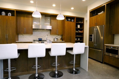 Inspiration for a large modern l-shaped concrete floor and gray floor eat-in kitchen remodel in Austin with an undermount sink, flat-panel cabinets, dark wood cabinets, quartz countertops, white backsplash, stainless steel appliances, an island and white countertops
