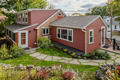 This is an example of a traditional one-storey red house exterior in Boston with vinyl siding, a gable roof and a shingle roof.