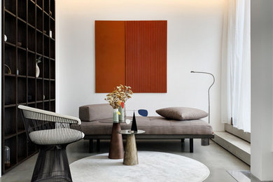 Inspiration pour un salon design avec une bibliothèque ou un coin lecture, sol en béton ciré, cheminée suspendue, un manteau de cheminée en plâtre et un sol gris.