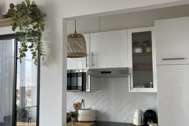 パリにあるお手頃価格の小さな北欧スタイルのおしゃれなキッチン (一体型シンク、インセット扉のキャビネット、白いキャビネット、木材カウンター、白いキッチンパネル、磁器タイルのキッチンパネル、黒い調理設備、グレーの床) の写真