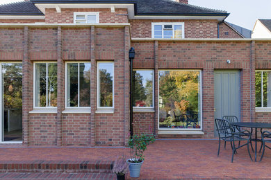 This is an example of a large contemporary backyard patio in Cambridgeshire with brick pavers and no cover.