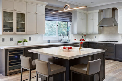 Large transitional l-shaped eat-in kitchen in San Francisco with a single-bowl sink, shaker cabinets, white cabinets, white splashback, stainless steel appliances, with island, grey floor and white benchtop.