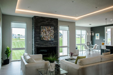 Example of a large trendy open concept medium tone wood floor and brown floor living room design in Cedar Rapids with gray walls, a standard fireplace, a stone fireplace and no tv