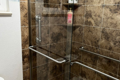 Example of a mid-sized transitional master brown tile laminate floor and multicolored floor sliding shower door design in Other