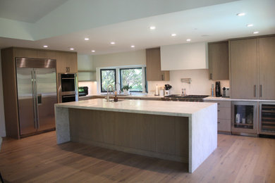 Large minimalist u-shaped light wood floor, brown floor and tray ceiling open concept kitchen photo in San Francisco with flat-panel cabinets, brown cabinets, granite countertops, stainless steel appliances, an island, white countertops and an undermount sink