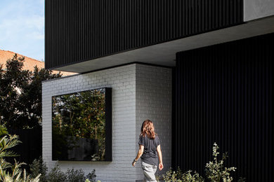 Modelo de fachada de casa negra minimalista de tamaño medio de dos plantas con revestimiento de madera, tejado plano y tejado de metal