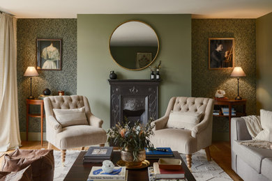 Inspiration for a medium sized classic formal living room in Other with green walls, medium hardwood flooring, a standard fireplace, a metal fireplace surround, no tv, brown floors and wallpapered walls.