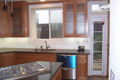 Photo of a mid-sized traditional kitchen in Sacramento with a single-bowl sink, recessed-panel cabinets, medium wood cabinets, granite benchtops, stainless steel appliances, ceramic floors, with island and brown floor.