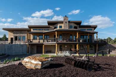 Inspiration for a mid-sized eclectic beige two-story stone house exterior remodel in Denver with a shed roof, a metal roof and a brown roof