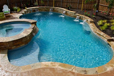 Imagen de piscinas y jacuzzis alargados actuales de tamaño medio a medida en patio trasero con adoquines de piedra natural