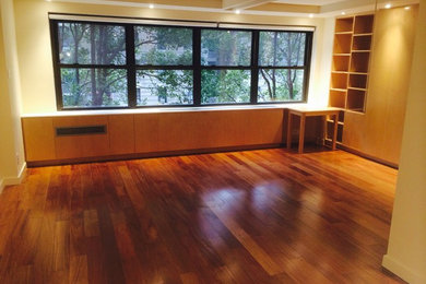 Example of a minimalist medium tone wood floor living room design in New York with white walls and a wall-mounted tv