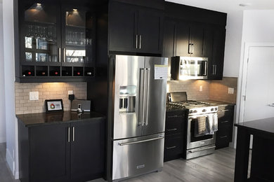 Example of a large minimalist l-shaped light wood floor open concept kitchen design in Calgary with a double-bowl sink, shaker cabinets, gray cabinets, wood countertops, beige backsplash, ceramic backsplash, stainless steel appliances and an island