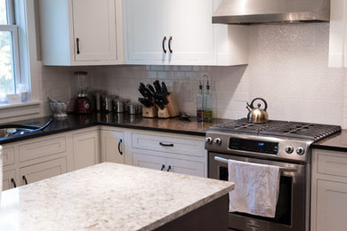 Transitional u-shaped eat-in kitchen photo in Milwaukee with shaker cabinets, white cabinets, white backsplash and an island