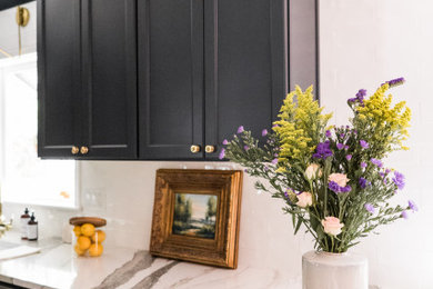 Example of a mid-sized transitional u-shaped laminate floor open concept kitchen design in Other with a farmhouse sink, black cabinets, quartzite countertops, white backsplash and a peninsula