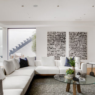 Design ideas for a midcentury walk-out basement in Los Angeles with white walls and light hardwood flooring.