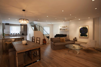 Example of a mid-sized minimalist open concept medium tone wood floor and beige floor living room design in New York with white walls, a standard fireplace, a plaster fireplace and a wall-mounted tv