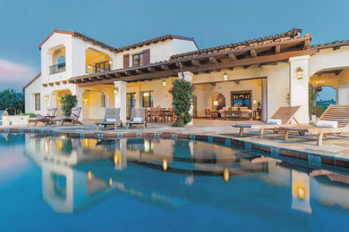 This is an example of an expansive mediterranean backyard custom-shaped pool in San Diego with natural stone pavers.