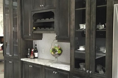 Photo of a large transitional single-wall wet bar in Toronto with recessed-panel cabinets, dark wood cabinets, granite benchtops, white splashback, mosaic tile splashback and white floor.
