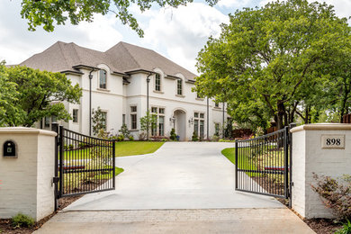 Photo of an expansive two-storey brick white house exterior in Dallas with a shingle roof and a hip roof.