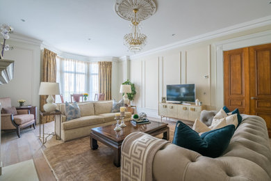Photo of an expansive classic formal and grey and cream living room with beige walls, medium hardwood flooring, a standard fireplace, a stone fireplace surround, a wall mounted tv, grey floors and panelled walls.