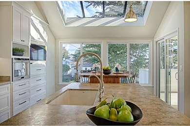 Example of a mid-sized classic l-shaped eat-in kitchen design in San Francisco with an undermount sink, recessed-panel cabinets, white cabinets, soapstone countertops, stainless steel appliances and an island