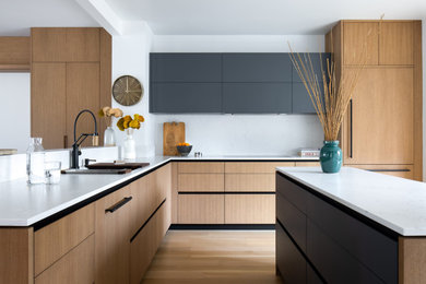 Photo of a contemporary u-shaped open plan kitchen in Philadelphia with an undermount sink, medium wood cabinets, quartz benchtops, panelled appliances, white benchtop, flat-panel cabinets, multi-coloured splashback, medium hardwood floors, with island and brown floor.