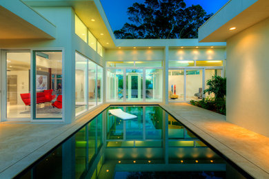 Inspiration for a mid-sized modern courtyard rectangular pool in Tampa with natural stone pavers.