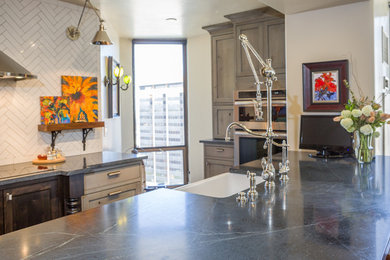 Inspiration for a small eclectic galley open plan kitchen in Denver with a farmhouse sink, recessed-panel cabinets, grey cabinets, soapstone benchtops, white splashback, ceramic splashback, stainless steel appliances, vinyl floors and a peninsula.