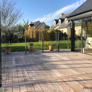 Agrandissement d'une terrasse en bois exotique avec un pare-vent en verre