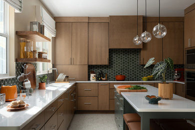 Mid-century modern u-shaped gray floor kitchen photo in DC Metro with an undermount sink, flat-panel cabinets, medium tone wood cabinets, stainless steel appliances, an island, white countertops and green backsplash