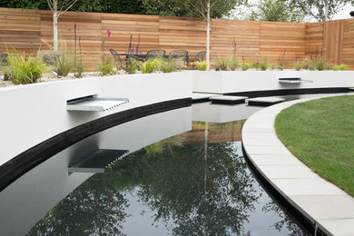 Photo of a medium sized contemporary back partial sun garden for summer in Other with a water feature and brick paving.