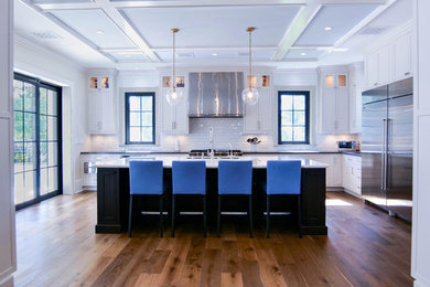 Large trendy u-shaped dark wood floor and brown floor enclosed kitchen photo in Miami with a drop-in sink, shaker cabinets, white cabinets, marble countertops, white backsplash, subway tile backsplash, stainless steel appliances, an island and white countertops