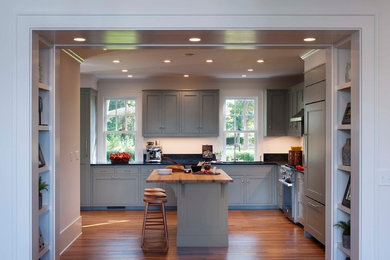 Design ideas for a large transitional u-shaped eat-in kitchen in Boston with a single-bowl sink, flat-panel cabinets, grey cabinets, soapstone benchtops, stone tile splashback, panelled appliances, medium hardwood floors and with island.