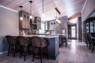 Mid-sized transitional u-shaped light wood floor eat-in kitchen photo in Chicago with a farmhouse sink, flat-panel cabinets, green cabinets, quartzite countertops, multicolored backsplash, stone tile backsplash, paneled appliances and an island