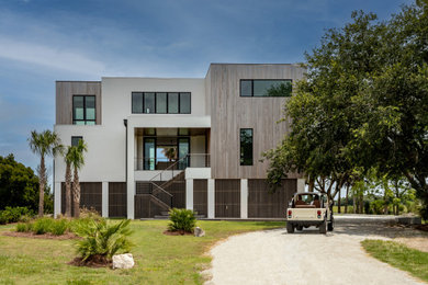 Inspiration for a mid-sized coastal white three-story stucco exterior home remodel in Charleston with a metal roof and a brown roof