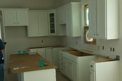 Foto de cocina de estilo americano de tamaño medio con armarios con paneles empotrados, puertas de armario blancas y una isla